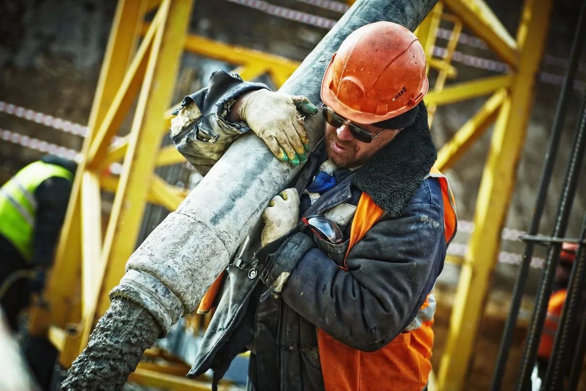 Concrete crew member handling a pour hose on a job site
